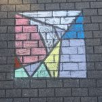 Kinder malen mit Kreide geometrische Figuren auf den Schulhof. 