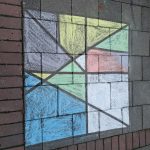 Kinder malen mit Kreide geometrische Figuren auf den Schulhof. 