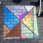 Kinder malen mit Kreide geometrische Figuren auf den Schulhof. 