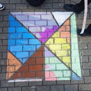 Kinder malen mit Kreide geometrische Figuren auf den Schulhof.