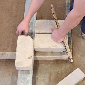 Die Kalk-Sandsteine müssen alle die gleiche Fugenbreite haben. Der Zollstock hilft dabei.