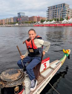 Mädchen sitzt auf dem Drachenboot an der Trommel